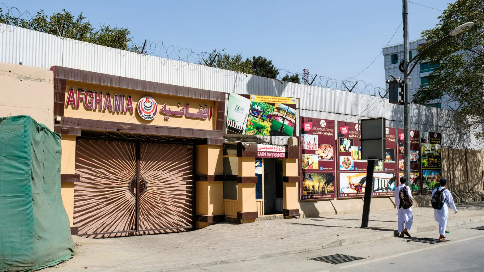 vusoká stěna s ostnatým drátem a velkou bránou