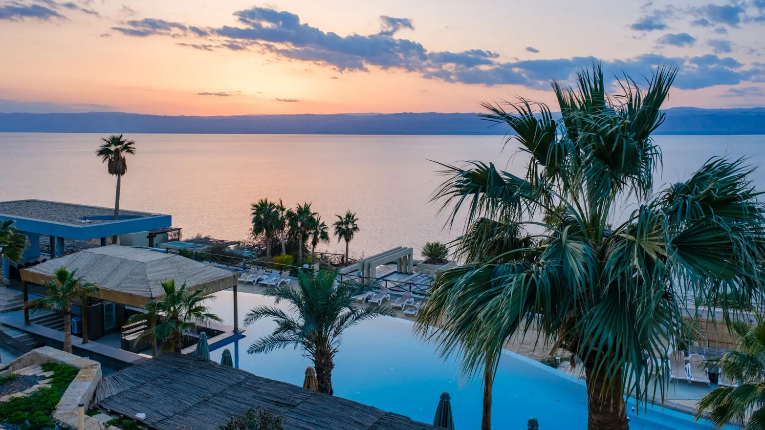 hotelový bazén, palmy a moře v pozadí