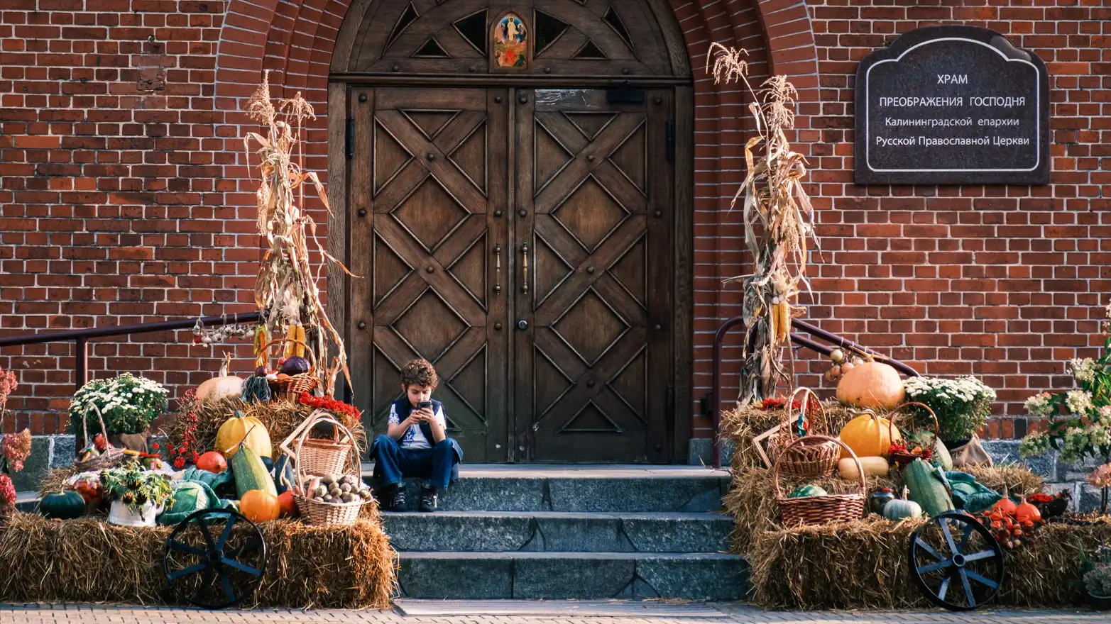 kluk sedící na schodech před vstupem do kostela