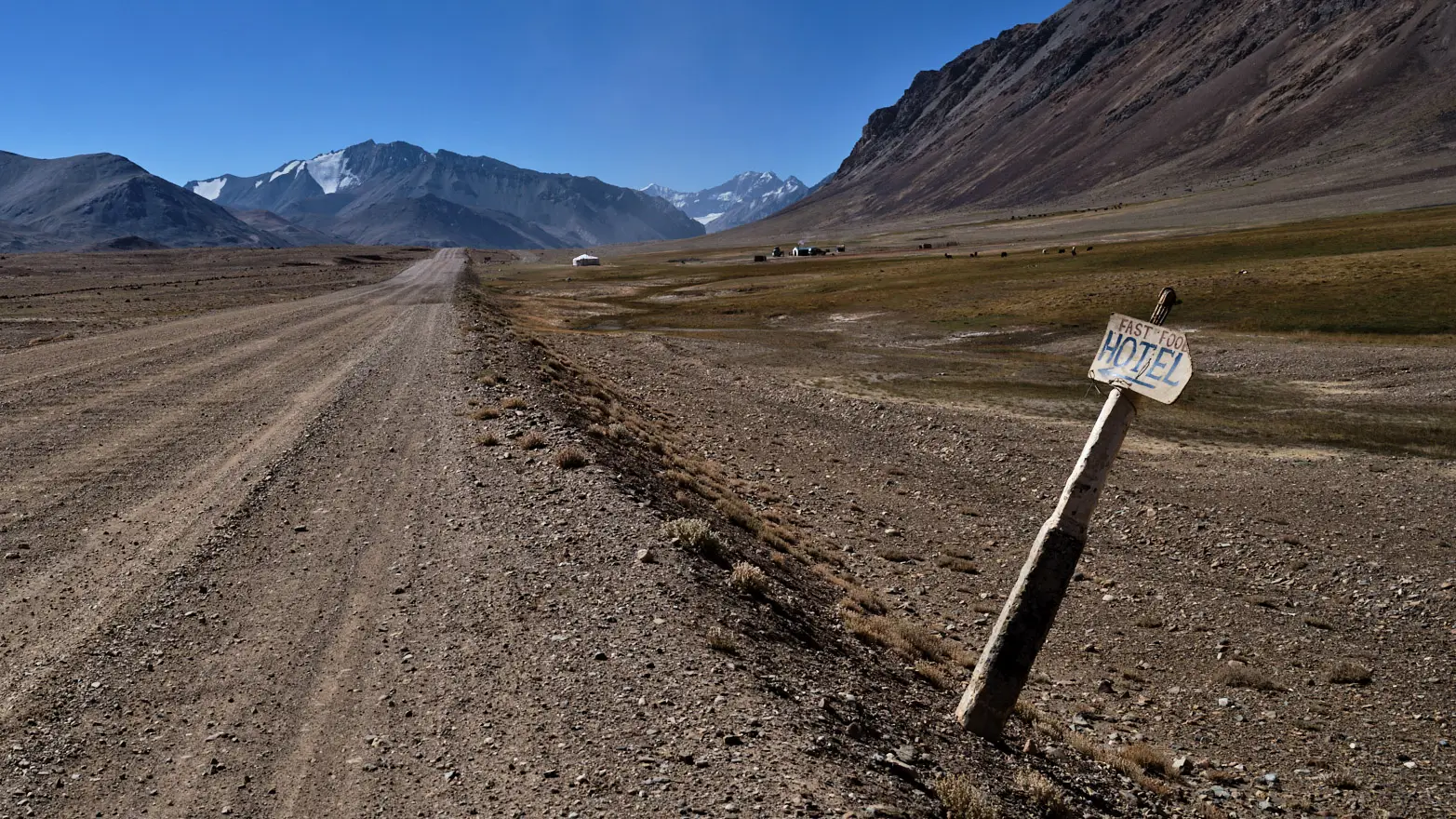 cedule inzerující hotel a fastfood na prašné cestě v odlehlých horách