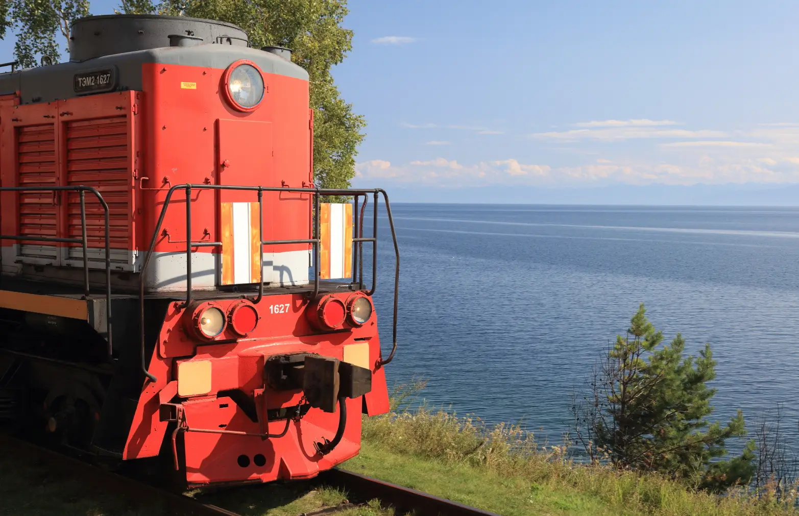 červená lokomotiva stojící před jezerem